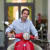 Mann auf roter Vespa