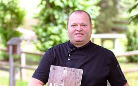 Frau im Blumenhemd vor einer Hecke