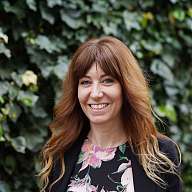 Frau im Blumenhemd vor einer Hecke