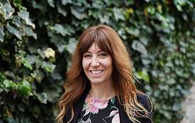 Frau im Blumenhemd vor einer Hecke